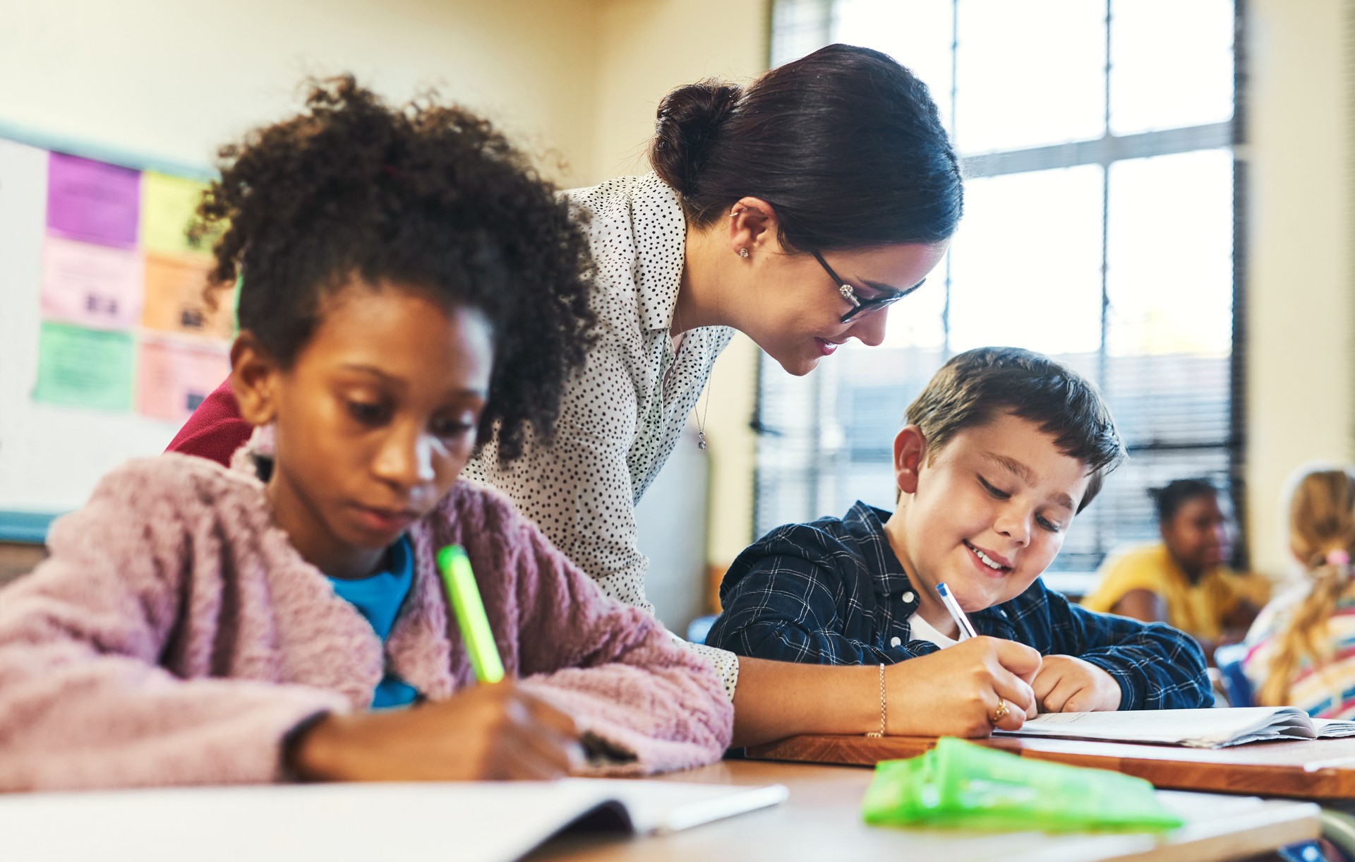 Shot of an attractive young teacher helping a student in her classroom during a lesson